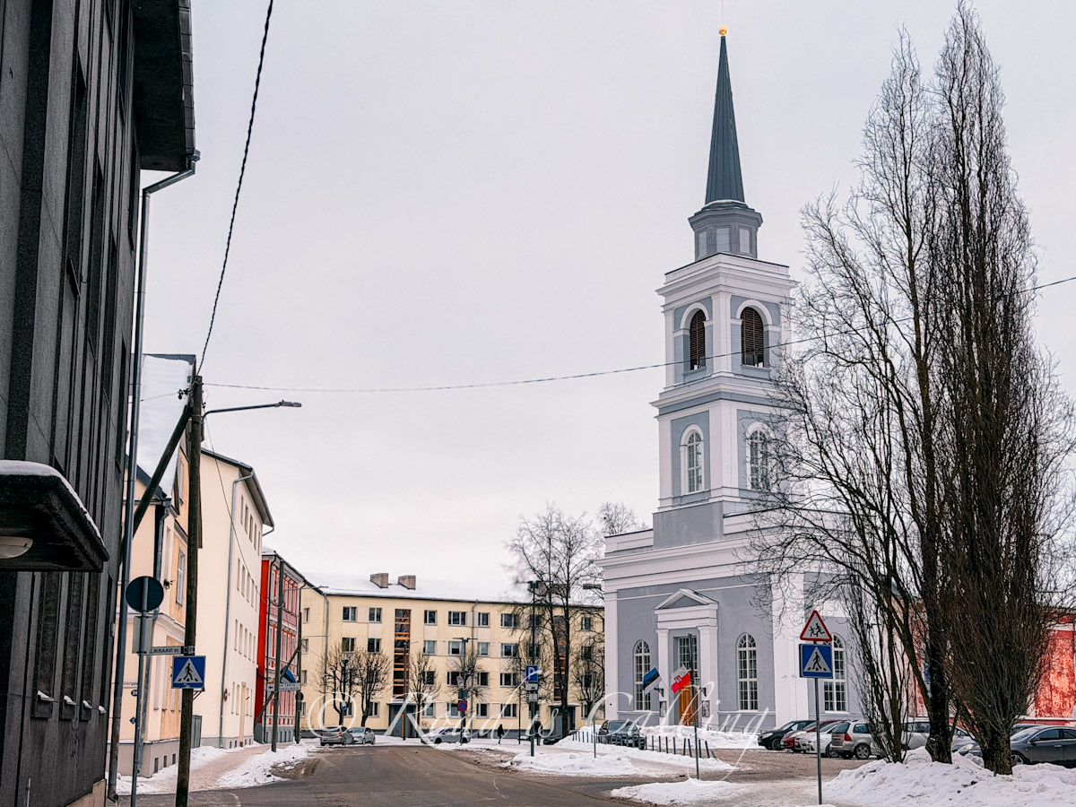 view of the residential street and church with snow by the road