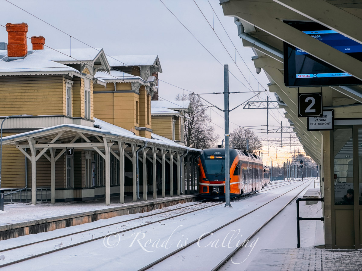 view of the Elron train on tracks by the old train station building in Tartu