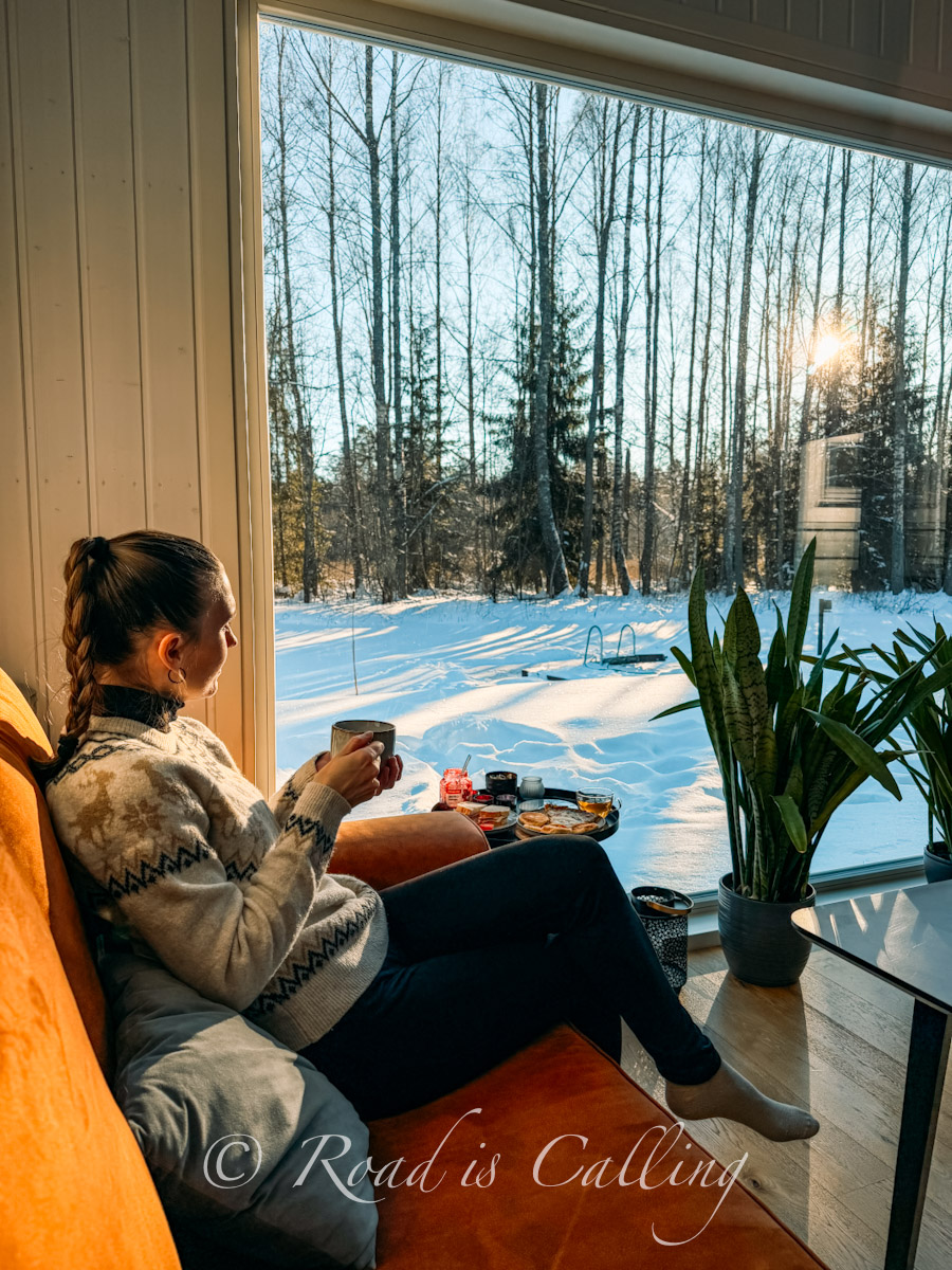 me sitting on the couch by the panoramic window in Lahemaa National Park, with the forest view outside te window