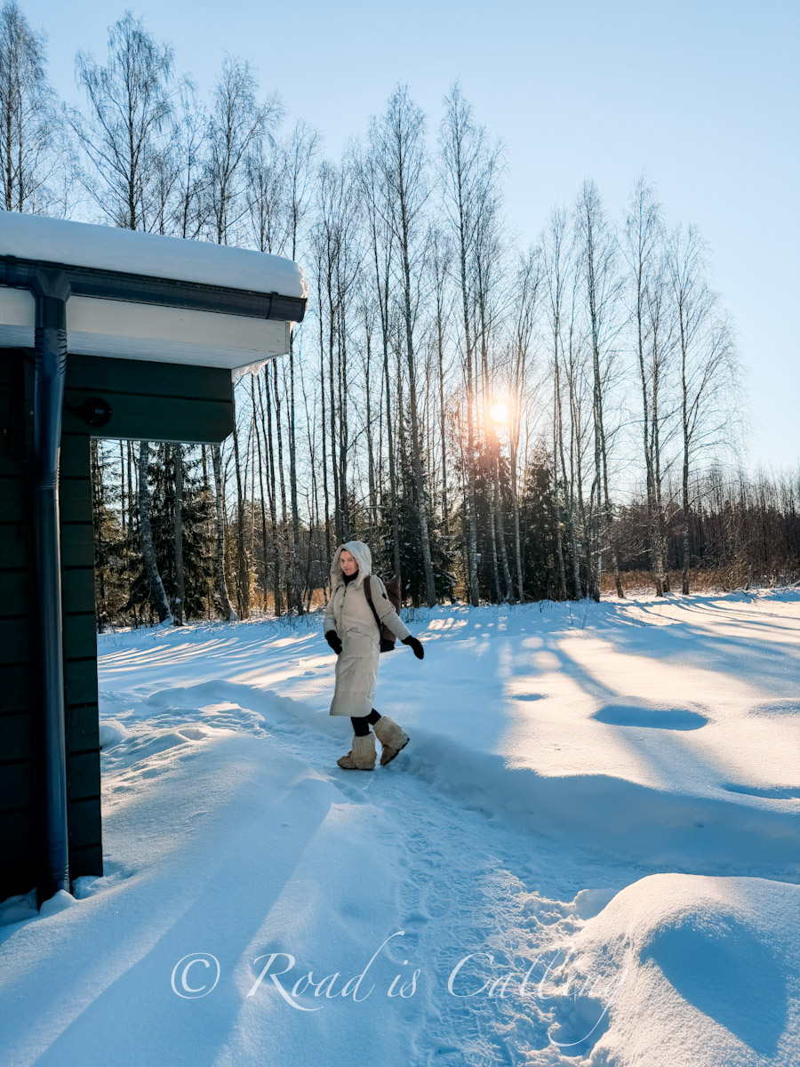 woman walking in deep snow at sunset by the cabin