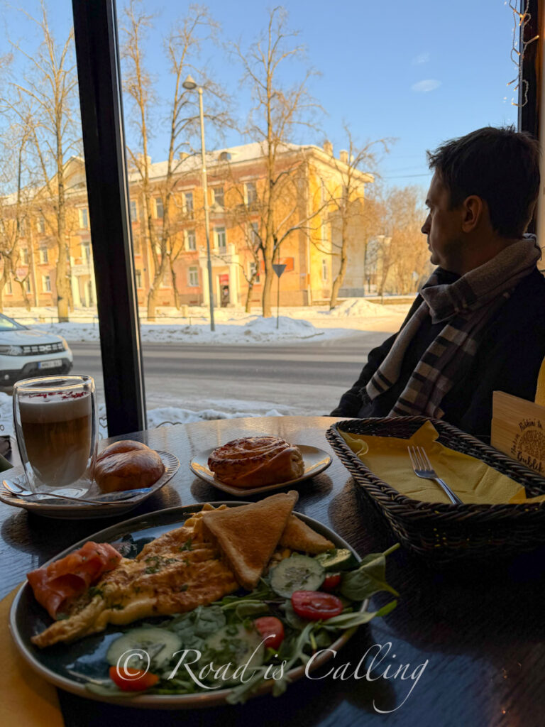 Mark sitting with breakfast by the window in a cozy cafe in Narva on a day trip from Tallinn