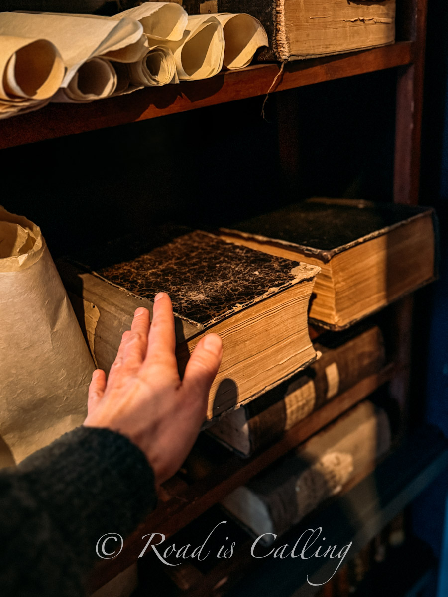 hand touching ancient books and rolled manuscripts in University of Tartu Museum
