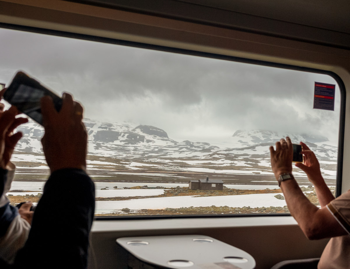 passengers take photos of the landscape outside the window on a train from Oslo to Bergen when traveling in Norway
