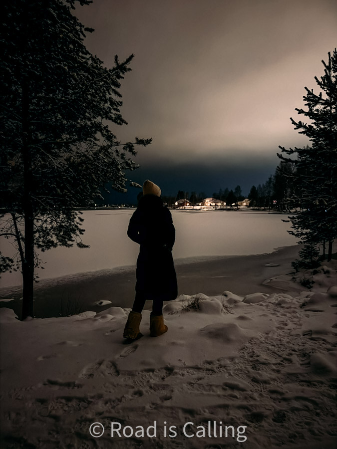 Me standing on snowy lakeshore at night in Rovaniemie during my 7 days in Lapland