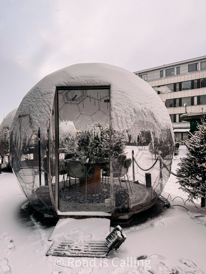 Snow-covered glass igloo restaurant pod in Rovaniemi Lapland Finland