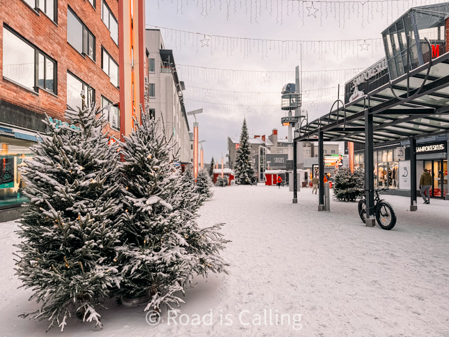 Snowy pedestrian street with Christmas trees and shops in Rovaniemi Finland