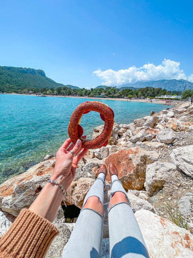 my hand holding simit with the view of the sea in Turkey in November