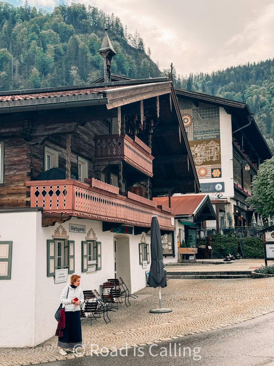 mom standing in front of the traditional Bavarian wooden chalets and mountains in Reit Im Winkl village