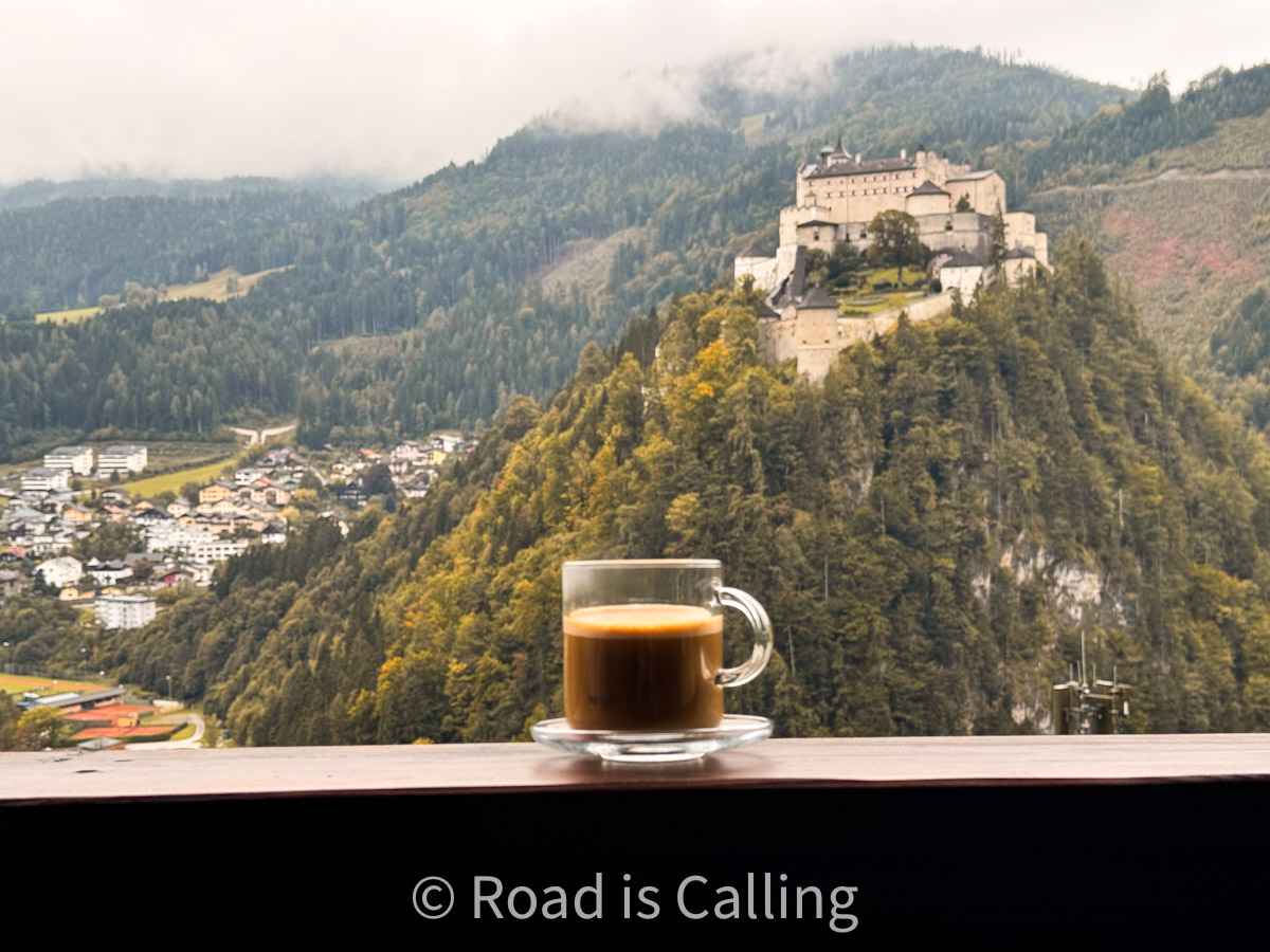 View of Hohenwerfen Castle and alpine valley with a cup of coffee in the foreground