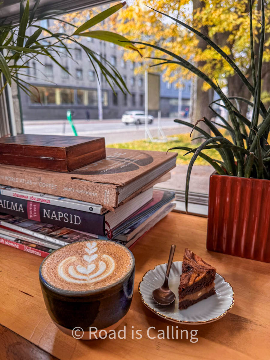 a cup of coffee, cake and books in a coffee shop