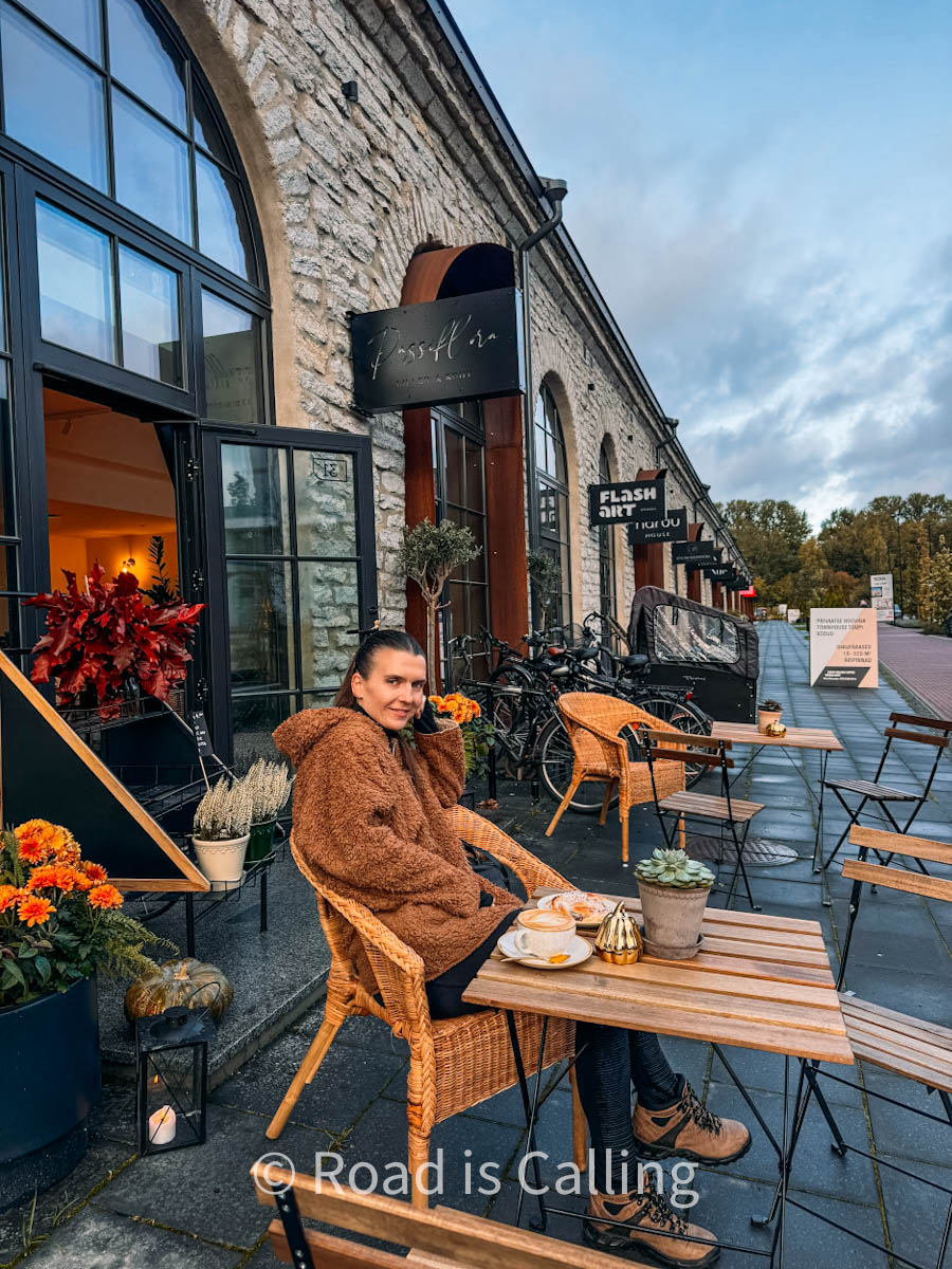 woman is sitting at the cafe table outside with coffee and pastry in Volta Tallinn