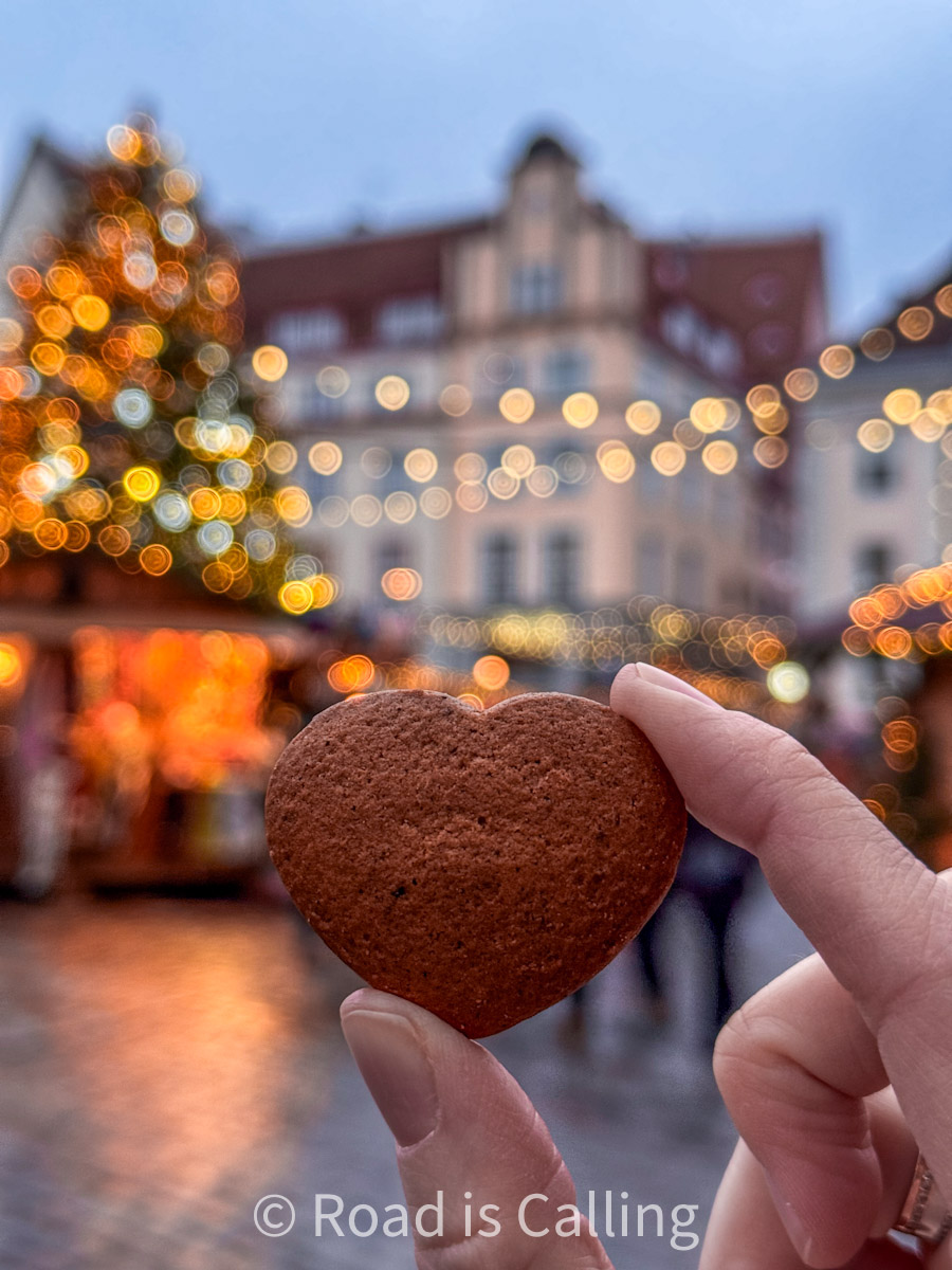hand holding gingerbread cookie in the form af heart with the Old Town in the background at Christmas