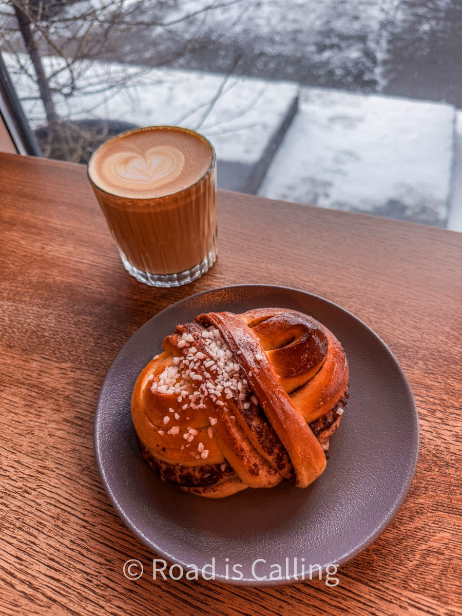 A cinnamon bun and a glass of cappuccino