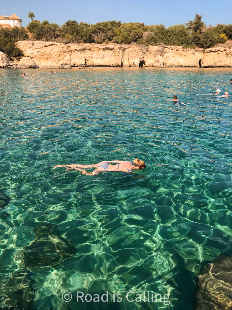 Person swimming in the sea near rocky coastline in Cyprus in November