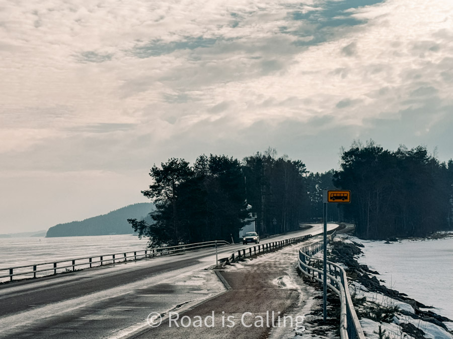 Scenic road along frozen lake with bus stop sign in Jyväskylä, Finland