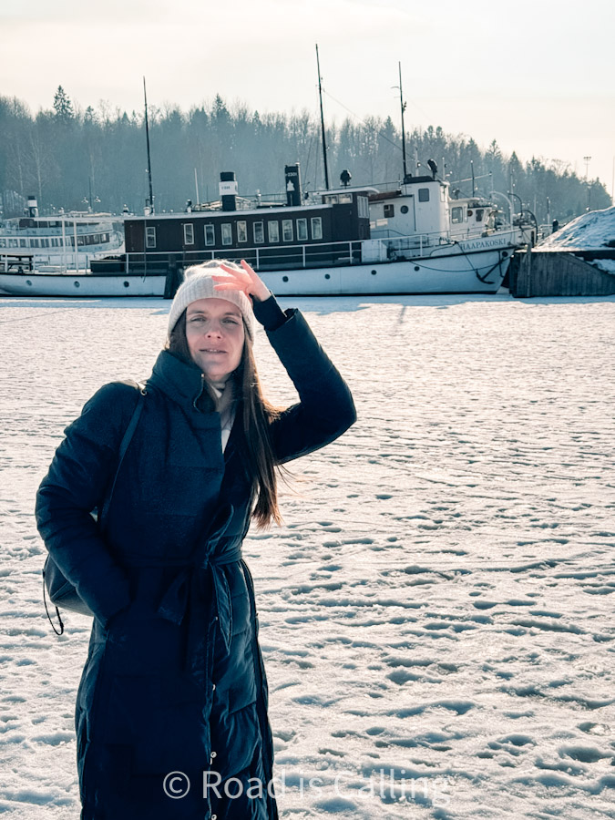 Woman in winter coat standing on snowy harbor with boats in Jyväskylä Finland