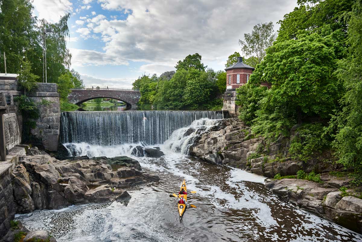 Kayaker paddling near waterfall and stone bridge in Helsinki Finland