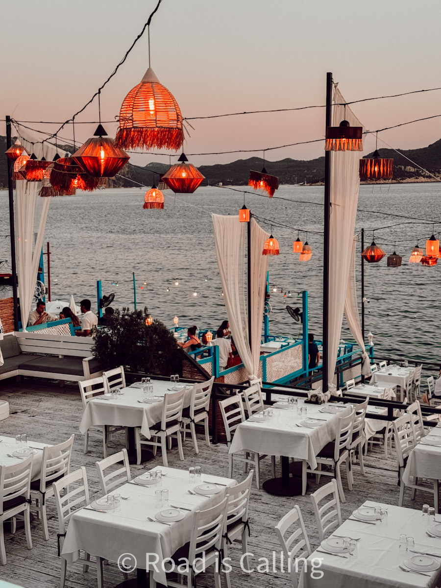 Seaside restaurant in Kaş, Turkey at sunset with warm lantern lighting and white table settings