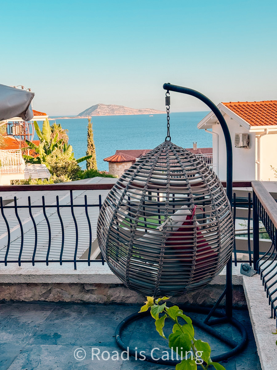 Seaview terrace with hanging egg chair and Mediterranean island in the distance in Kaş, Turkey