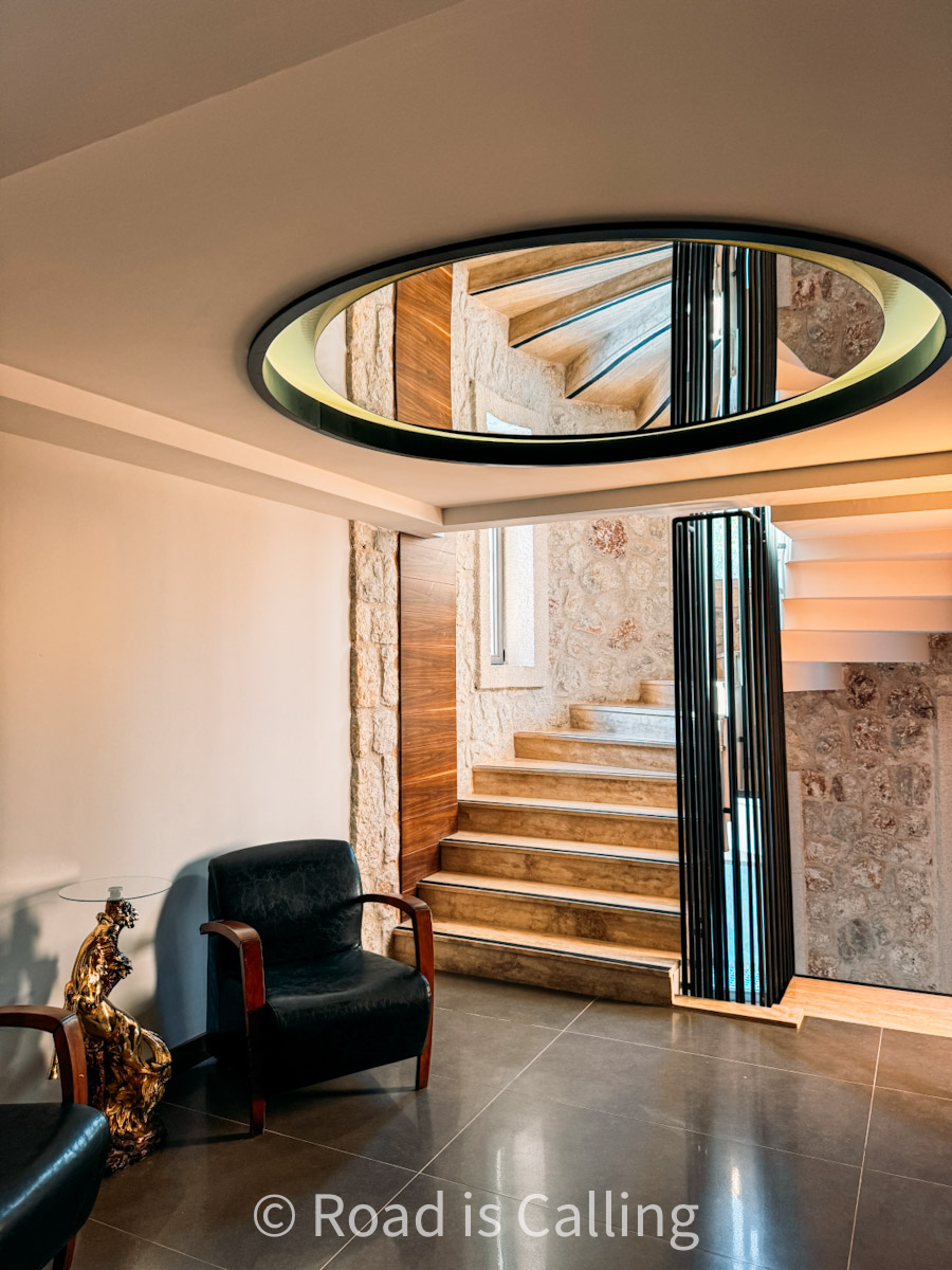 Stylish hotel interior in Kaş, Turkey with stone walls, spiral staircase, and modern circular mirror