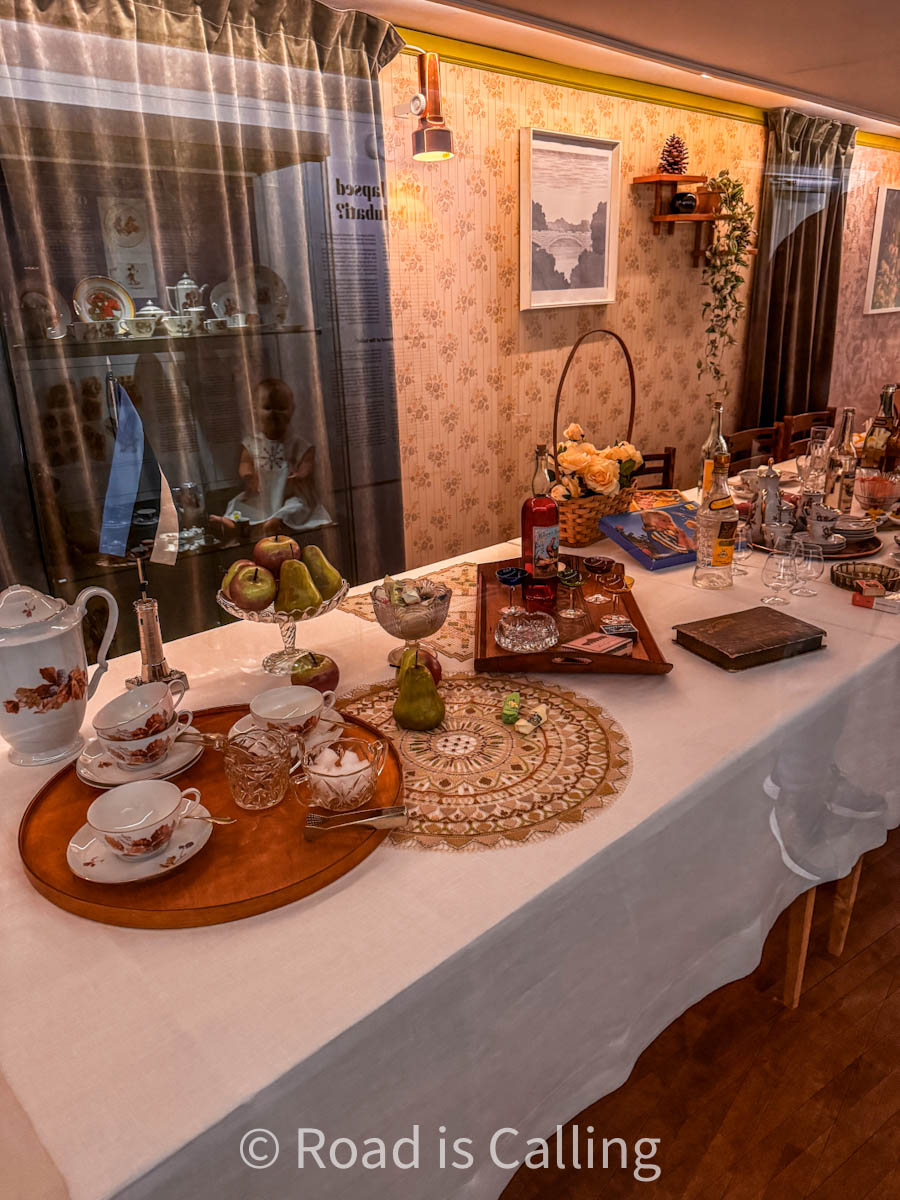 Vintage-style Estonian dining table setup in a museum exhibit with dishes, drinks, and retro decor