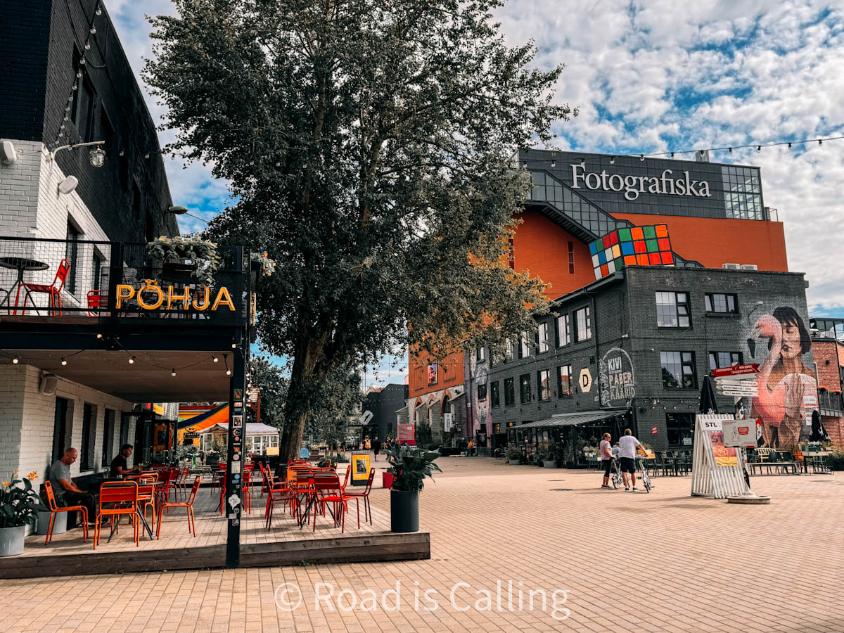 Open square in Telliskivi Creative City with outdoor cafes, Fotografiska museum, and colorful street art