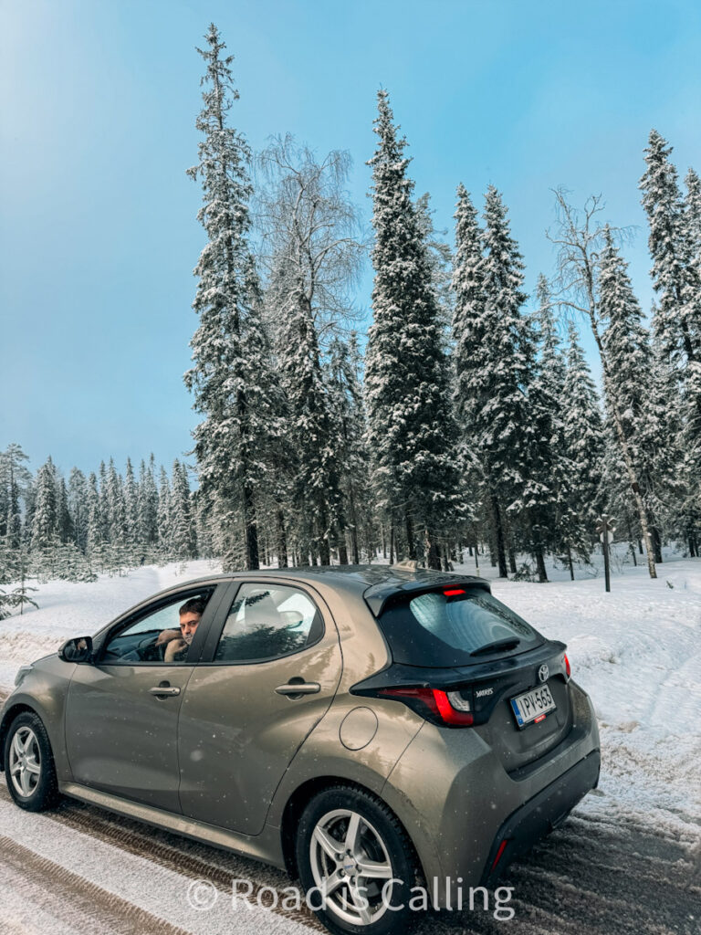 Tourist driving a rental car in Rovaniemi through snowy Lapland forest