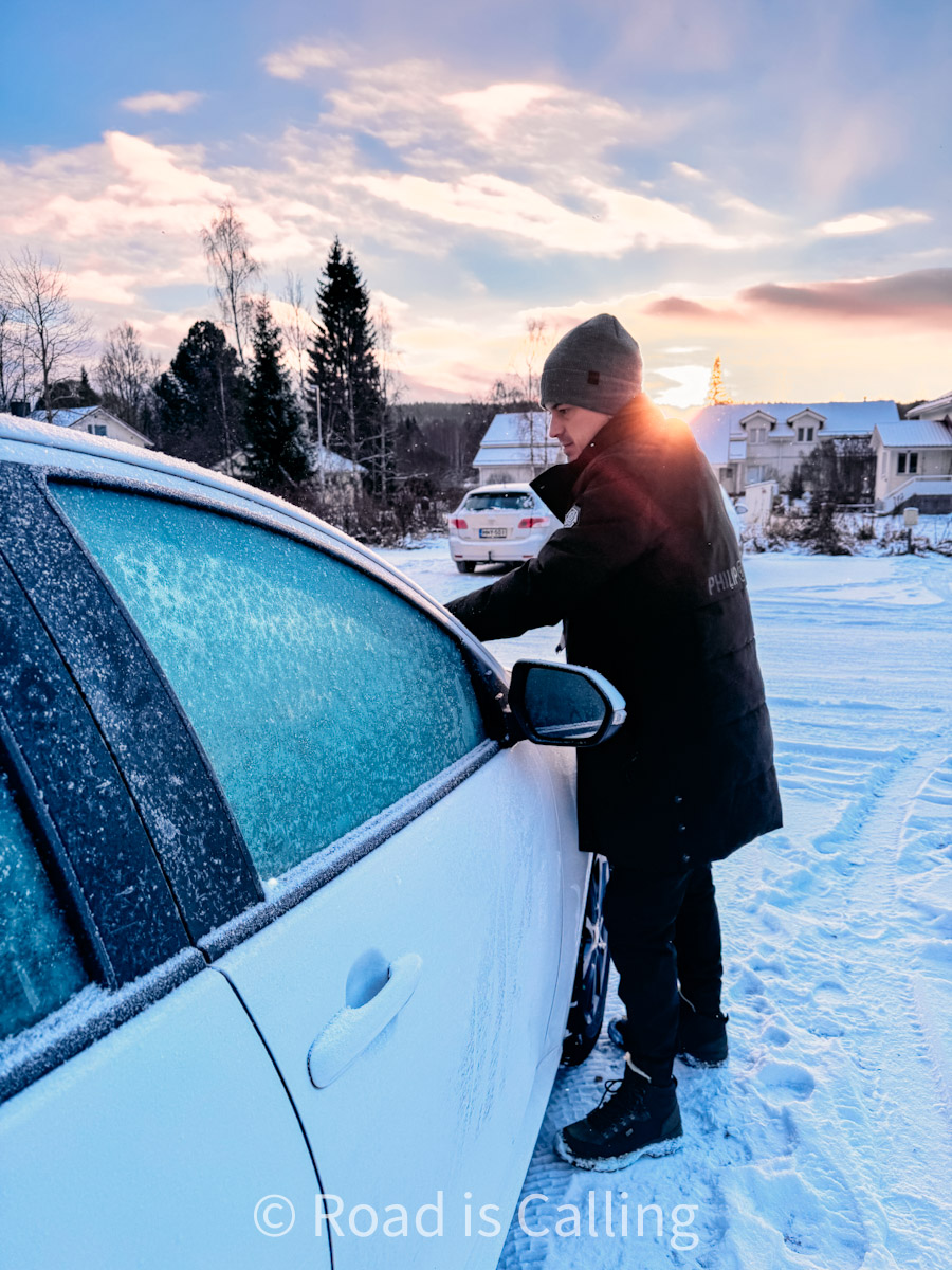 Traveler cleaning snow from rental vehicle in Rovaniemi - winter driving preparations in Lapland