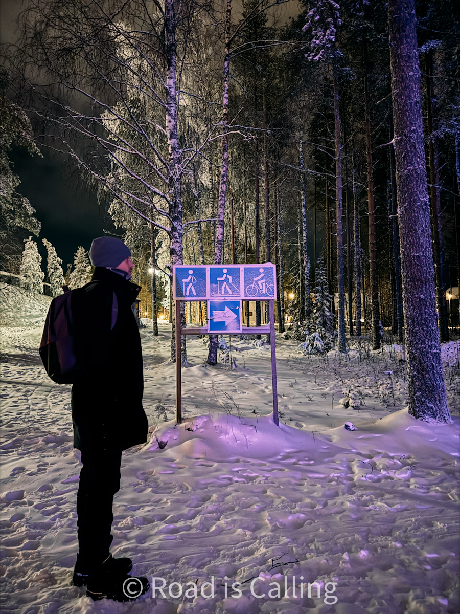 person looking at information board in snowy forest