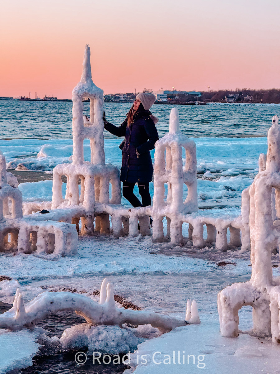 Woman standing next to frozen ice sculptures by the sea during winter sunset in Tallinn