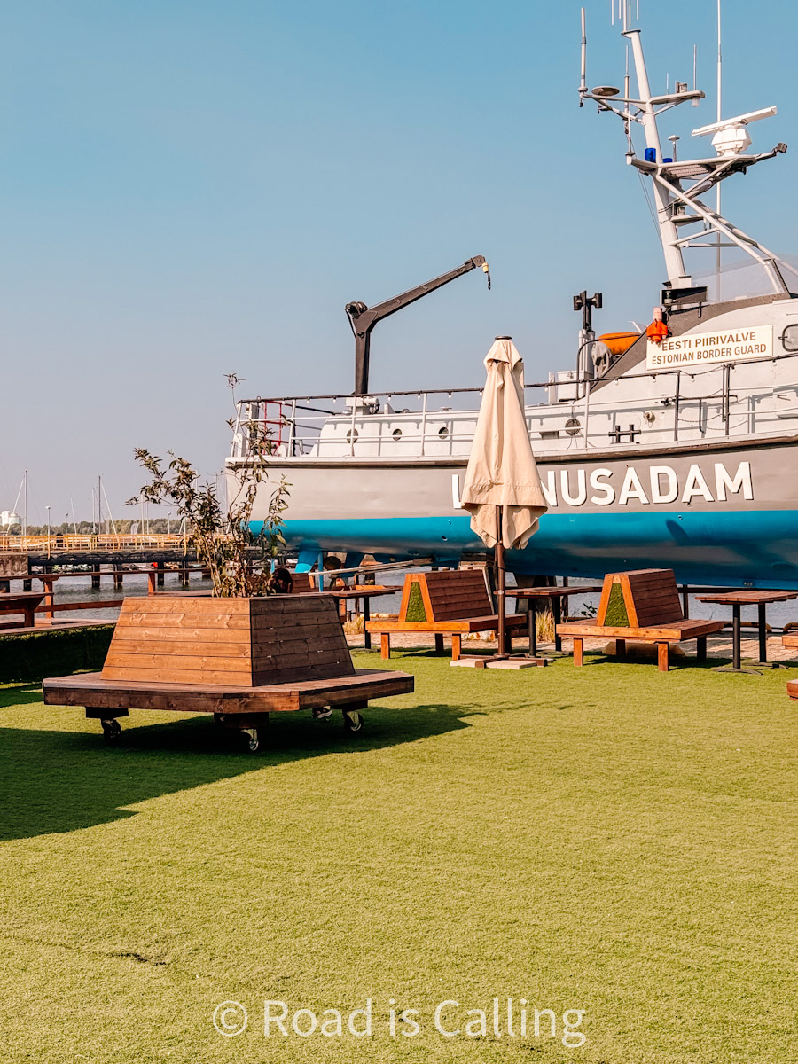 Outdoor seating at Lennusadam Seaplane Harbour with Estonian Border Guard ship docked nearby