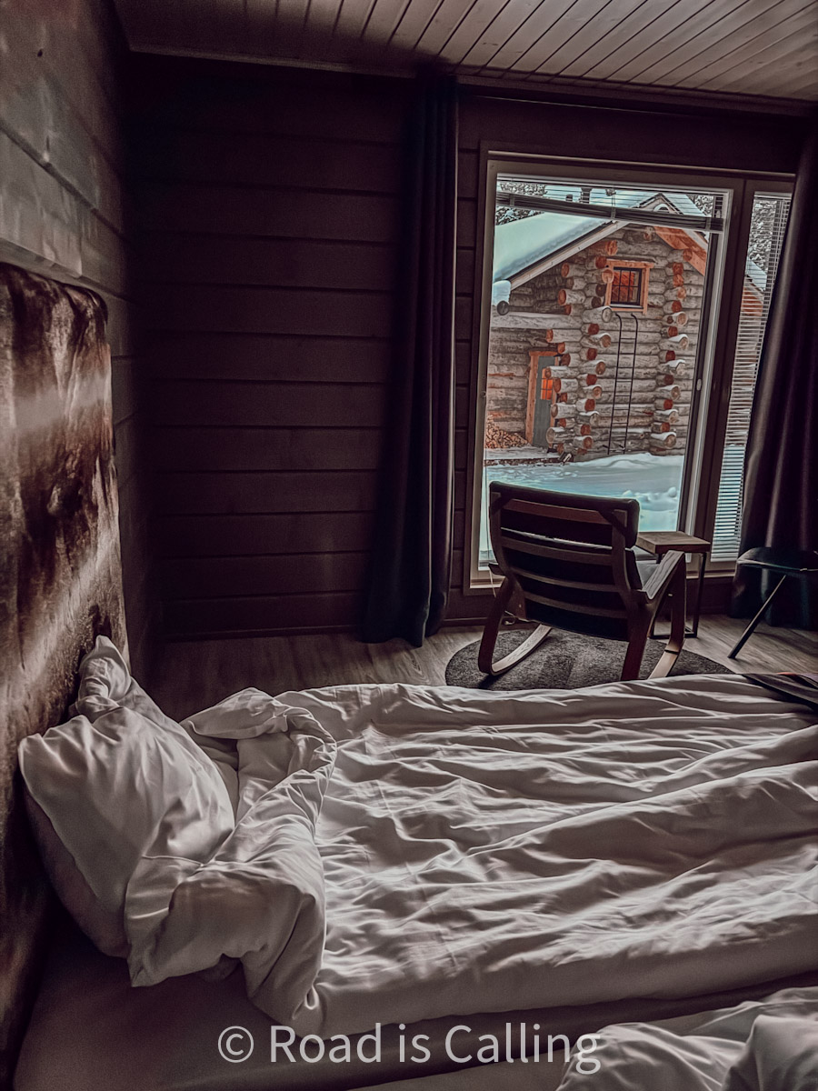 bed with blanket and pillow together with the chair by the window of a hotel room