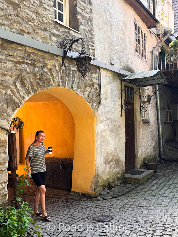 me standing under medieval archway on cobblestone street in Tallinn Old Town