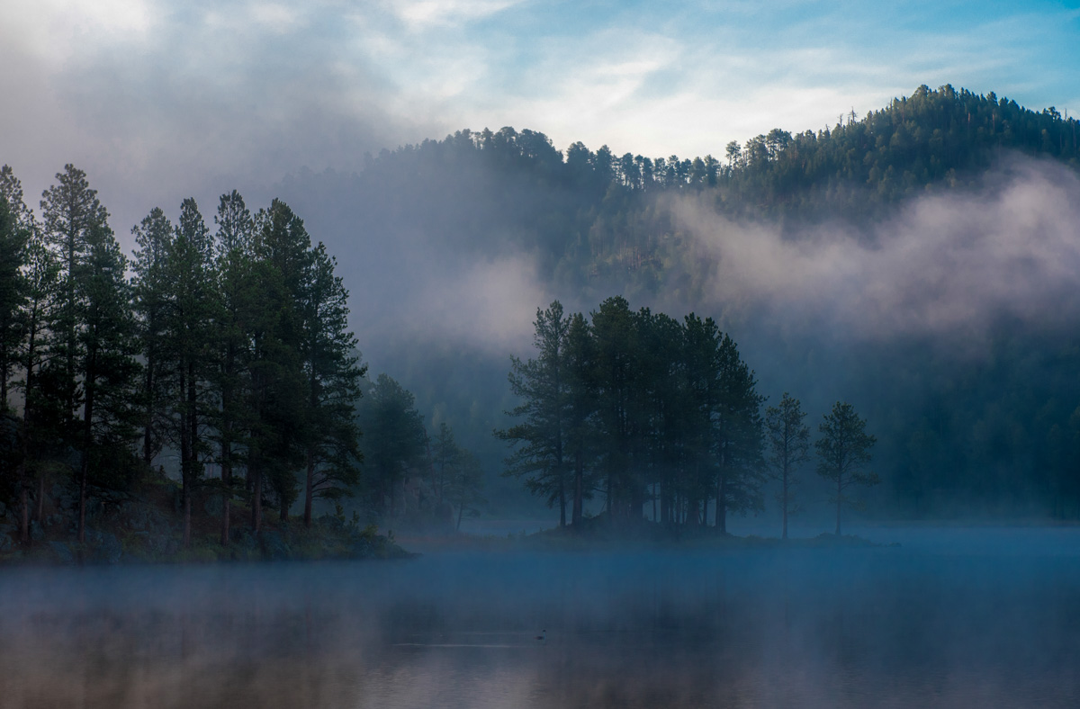 sunrise over the lake with a mist around the trees