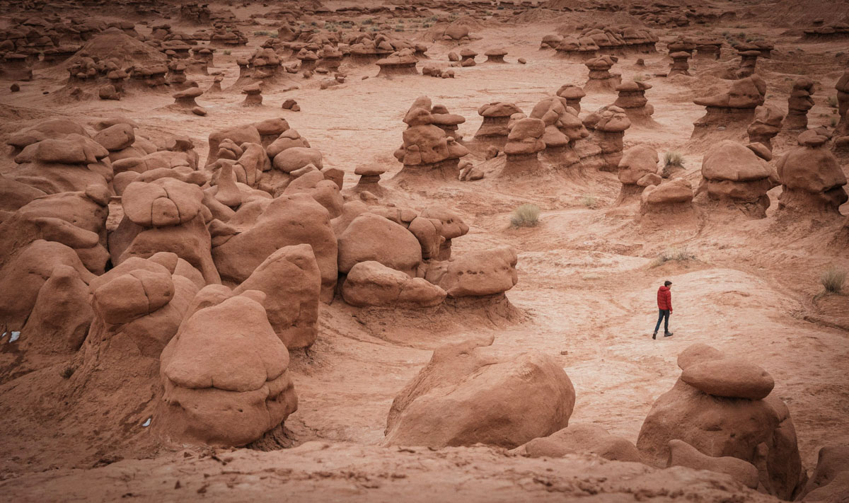 man walking between unusual rock formations in Goblin Valley State Park